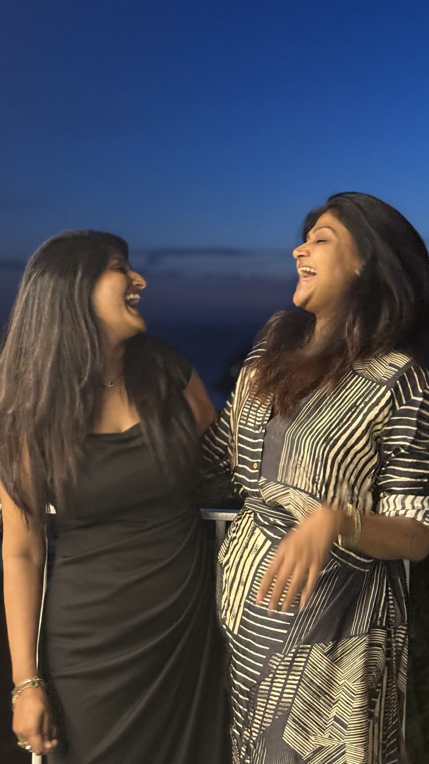 Two friends laughing freely together outdoors at dusk