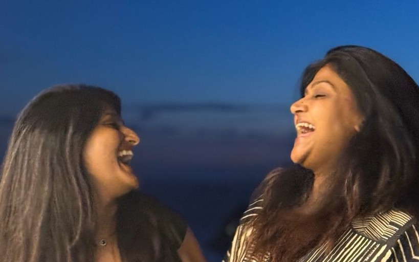 Two friends laughing freely together outdoors at dusk